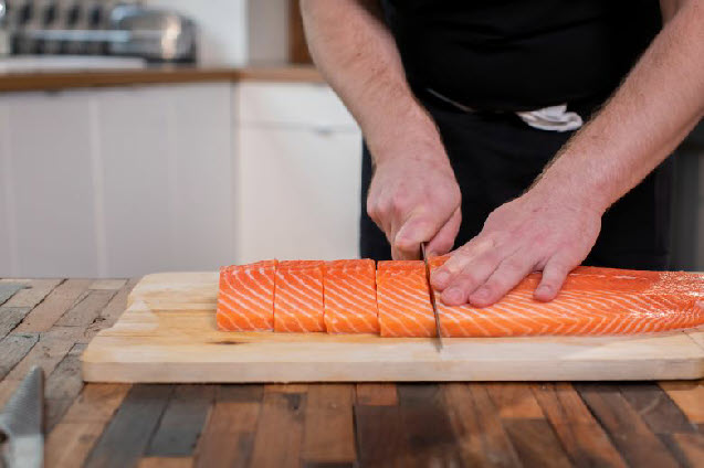 Man slicing a side of salmon